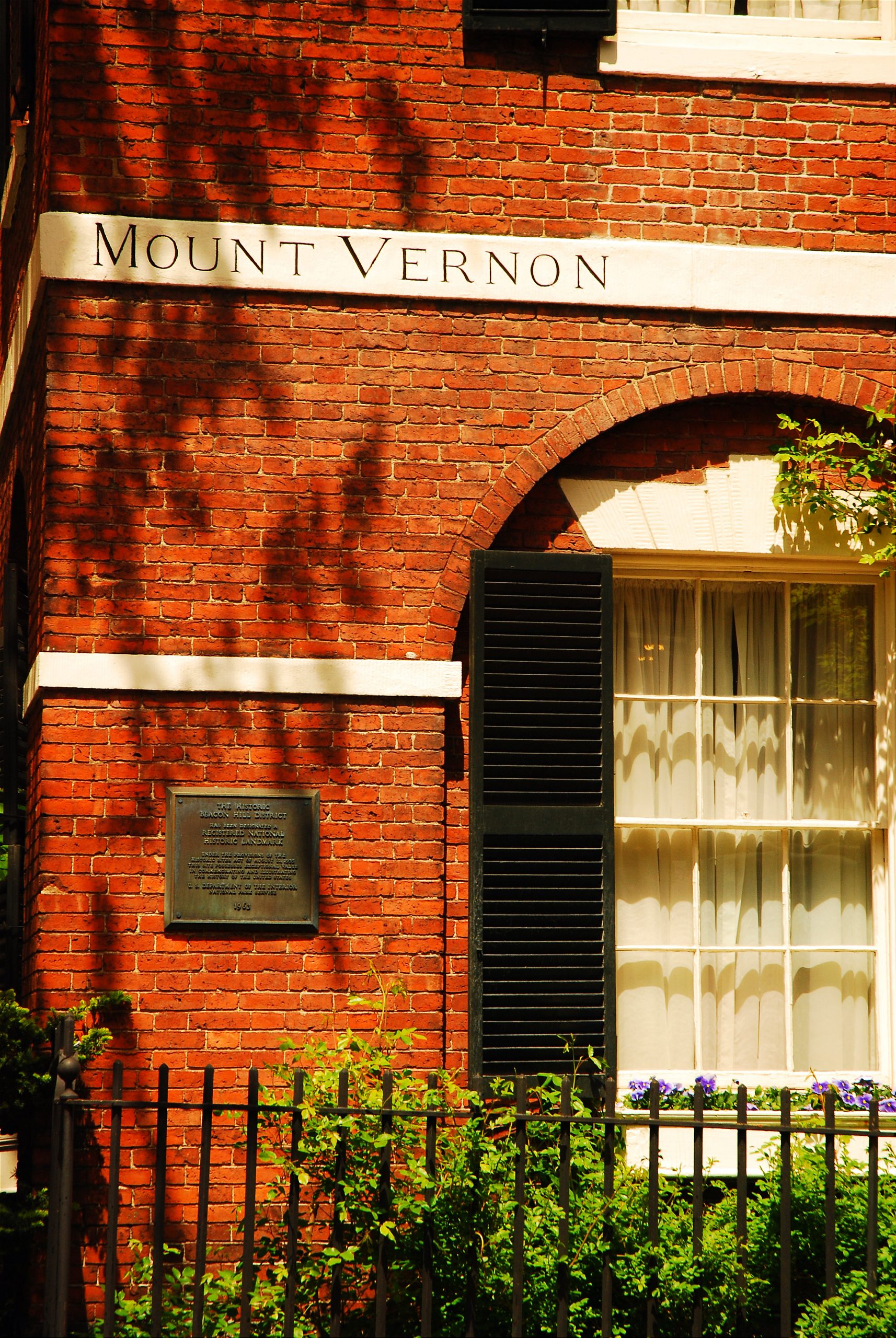 View of the south facade of the Nichols House Museum. The words "Mount Vernon" inscribed on the white belt course on the brick wall. The National Historic Landmark plaque is visible.